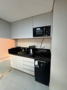 a kitchen with a microwave and a black counter top at Apartamento 121 - Home in Ribeirão Preto