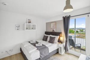 Un dormitorio blanco con una cama y un balcón. en Go2Cozy - Study & Work Apartments - WIFI - Kitchen, en Kaiserslautern