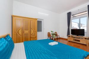 a bedroom with a blue bed and a television at Ann Homestay Vũng Tàu in Vung Tau