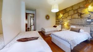 a bedroom with two beds and a stone wall at Vivenda Center Porto in Porto