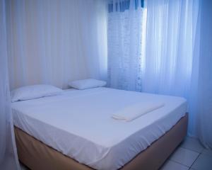 a white bedroom with a bed with white curtains at Serena Road Villa B in Shanzu