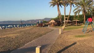 a walkway next to a beach with palm trees at Seafront Escape in Latchi in Polis Chrysochous