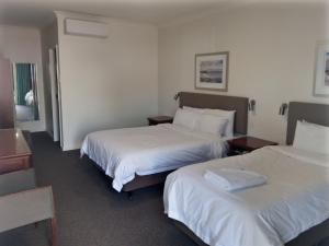 a hotel room with two beds with white sheets at Pastoral Hotel Motel in Port Augusta