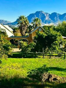 a house in a field with mountains in the background at Simunye Cottage in Simondium