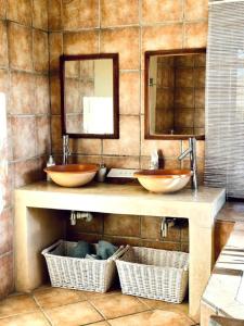 two sinks in a bathroom with two mirrors and baskets at Simunye Cottage in Simondium +5 photos