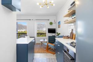 cocina con armarios azules y sala de estar. en Summerville Beach Loft by Host Agents, en Ciudad del Cabo