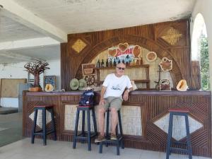 a man sitting on a stool in front of a bar at MAHAMBO BEACH hôtel in Mahambo