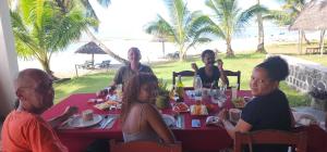 a group of people sitting around a table at the beach at MAHAMBO BEACH hôtel in Mahambo