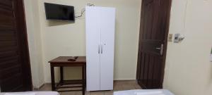 a white cabinet in a room with a table and a tv at HOTEL TROPICAL in Cuiabá