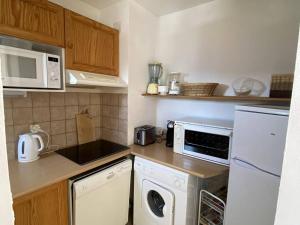 a small kitchen with a washer and dryer at Appartement T2 avec balcon, cuisine équipée, parking - FR-1-593-28 in Les Angles +2 photos