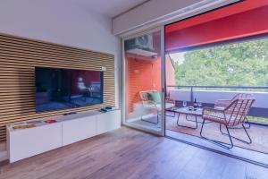 un soggiorno con grande TV, tavolo e sedie di Rio Verde - Milano 3 a Basiglio