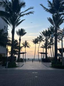 a street with palm trees and the ocean at sunset at Hollywood Townhouse steps to beach and famous Broadwalk in Hollywood Beach