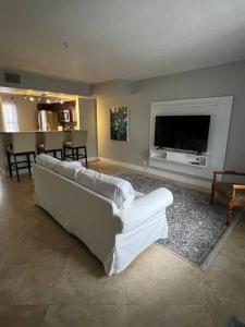 a living room with a white couch and a flat screen tv at Hollywood Townhouse steps to beach and famous Broadwalk in Hollywood Beach