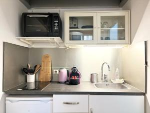 a small kitchen with a sink and a microwave at Appartement Grand Place de Lille - 2 voyageurs in Lille +6 photos