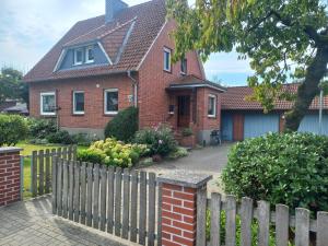 a red brick house with a wooden fence at Ferienwohnung Olendorp in Hermannsburg