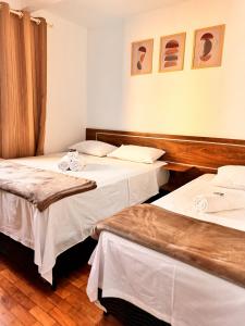 two beds in a hotel room with two tables at Hotel Real Cruzilia in Cruzília