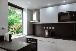 a kitchen with black and white cabinets and a window at BarraZen-Lofts-2-Netflix in Cayenne
