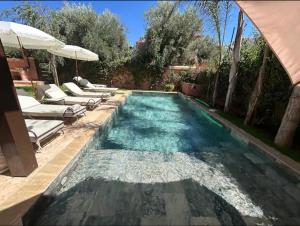 une piscine avec des chaises longues et un parasol dans l'établissement Villa golf amelkis Marrakech, à Sfiani 10 autres photos