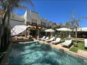 - une piscine avec des chaises et des parasols à côté d'une maison dans l'établissement Villa golf amelkis Marrakech, à Sfiani