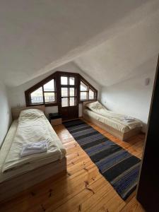 an attic bedroom with two beds and a rug at Чемерникъ in Gabrovnitsa +23 photos