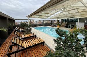 two benches sitting on a deck next to a swimming pool at Hotel Bicentenario Suites & Spa in San Miguel de Tucumán