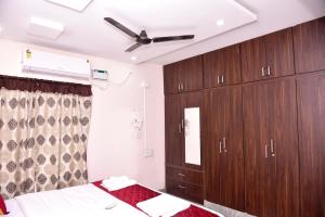 蒂鲁帕蒂SHALOM RESIDENCE - 2BHK-AC Service Apartments, Premium amenities, Kitchen with Stovetop, WiFi的一间卧室配有木制橱柜和吊扇
