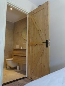 a bathroom with a wooden door and a sink at B&B Aan de Vaart in Bovensmilde