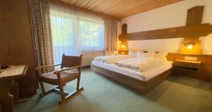 a bedroom with a large bed and a chair at Apart - und Frühstückspension Jägerheim in Kaunertal