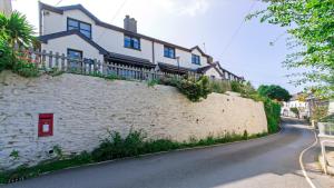 a house on a stone wall next to a street at Rockham Bay View - Sleeps 6 Mortehoe in Mortehoe