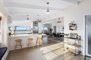 a kitchen and living room with a counter and stools at Beachfront Retreat in Mount Maunganui