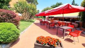 a patio with tables and chairs and a red umbrella at Casa Carla in Peschiera del Garda
