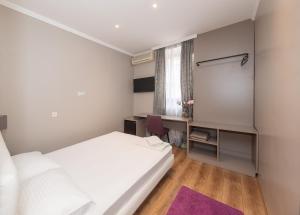 una piccola camera con letto bianco e scrivania di Garni Hotel Mediteraneo a Novi Sad