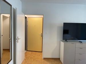 Zimmer mit einem TV und einer Tür mit einem Spiegel in der Unterkunft Bright and practical Studio - Art 16 in Zürich