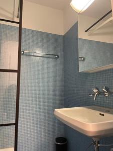 ein blau gefliestes Bad mit einem Waschbecken und einem Spiegel in der Unterkunft Bright and practical Studio - Art 16 in Zürich