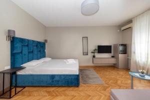 una camera con un grande letto con testiera blu di Garni Hotel Mediteraneo a Novi Sad