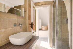 een badkamer met een bad en een glazen douche bij Giona's guest house by IL PUMO DI PUGLIA in Martina Franca