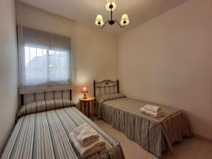 two twin beds in a room with a window at Apartamentos Miguel Angel in Beteta