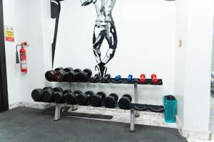 a rack with dumbbells and a man in the background at Luxury Hotel Deluxe Room - Sleeps 2 - Gym - Pool in Lekki