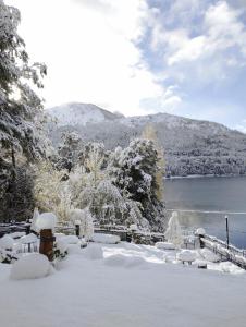 a snow covered yard with a view of a lake at Hosteria El Condado in San Carlos de Bariloche