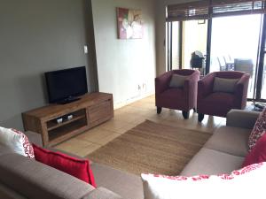sala de estar con sofá, TV y sillas en 601 Bali Hai, en Westbrook