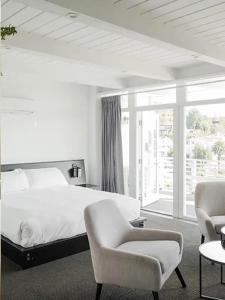 a white bedroom with a bed and two chairs at Hollywood Hills Hotel in Los Angeles