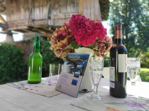 a table with a bottle of wine and a vase with flowers at Casa Loli-Villar in Luarca