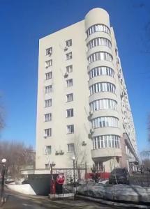 a tall white building with a stop sign in front of it at Large Green Apartment in Oral
