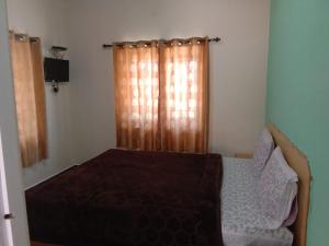 a bedroom with a bed and a window with curtains at Stay awhile in Ooty +13 photos