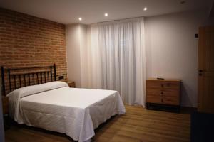 a bedroom with a white bed and a brick wall at Alojamiento Rural La Josefa de los Arribes in Fermoselle