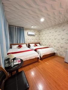 a bedroom with two beds and a table with a table at Phúc Đạt Container in Vung Tau