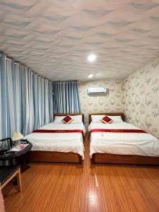 two beds in a room with blue curtains at Phúc Đạt Container in Vung Tau