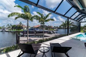 a house with a pool and a boat in the water at New Listing I Luxurious Waterfront 4 Bed Island Retreat in Marco Island