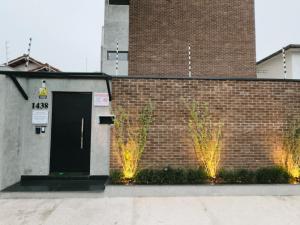 a brick wall with a black door and two plants at Apê Brooklin -Berrini in São Paulo