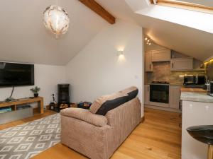 a living room with a couch and a kitchen at Low Fold Cottage in Penrith